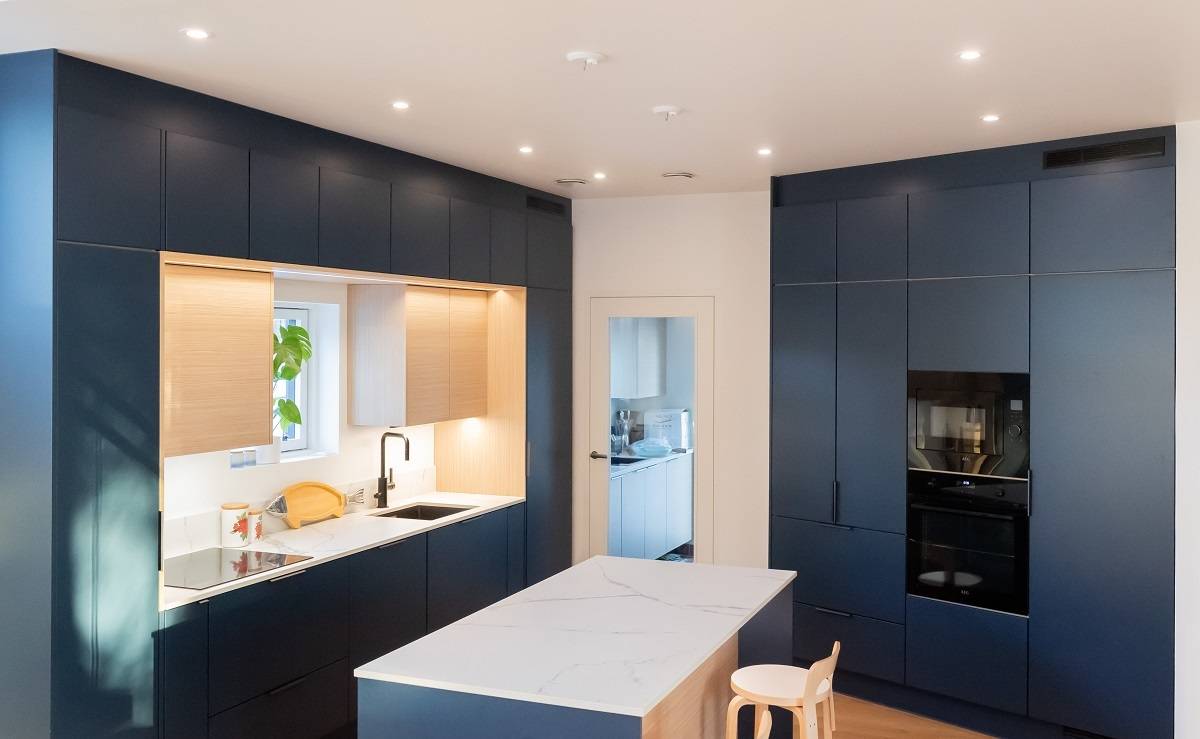 Les spots au plafond de cette cuisine ouverte sont disposés en anneau devant les armoires sur deux murs.